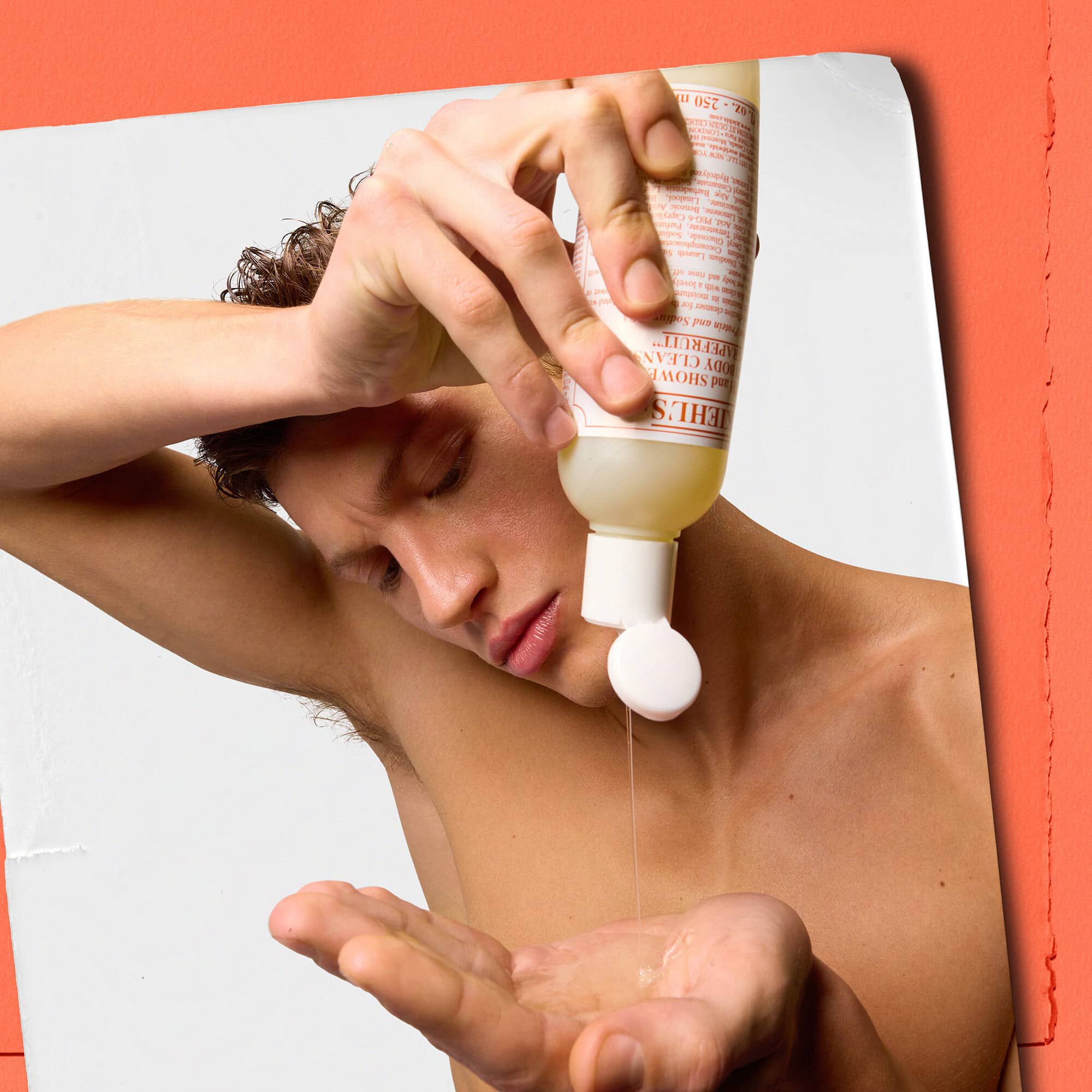 Модел, изливащ течен почистващ продукт за тяло с грейпфрут Kiehl's в ръката си