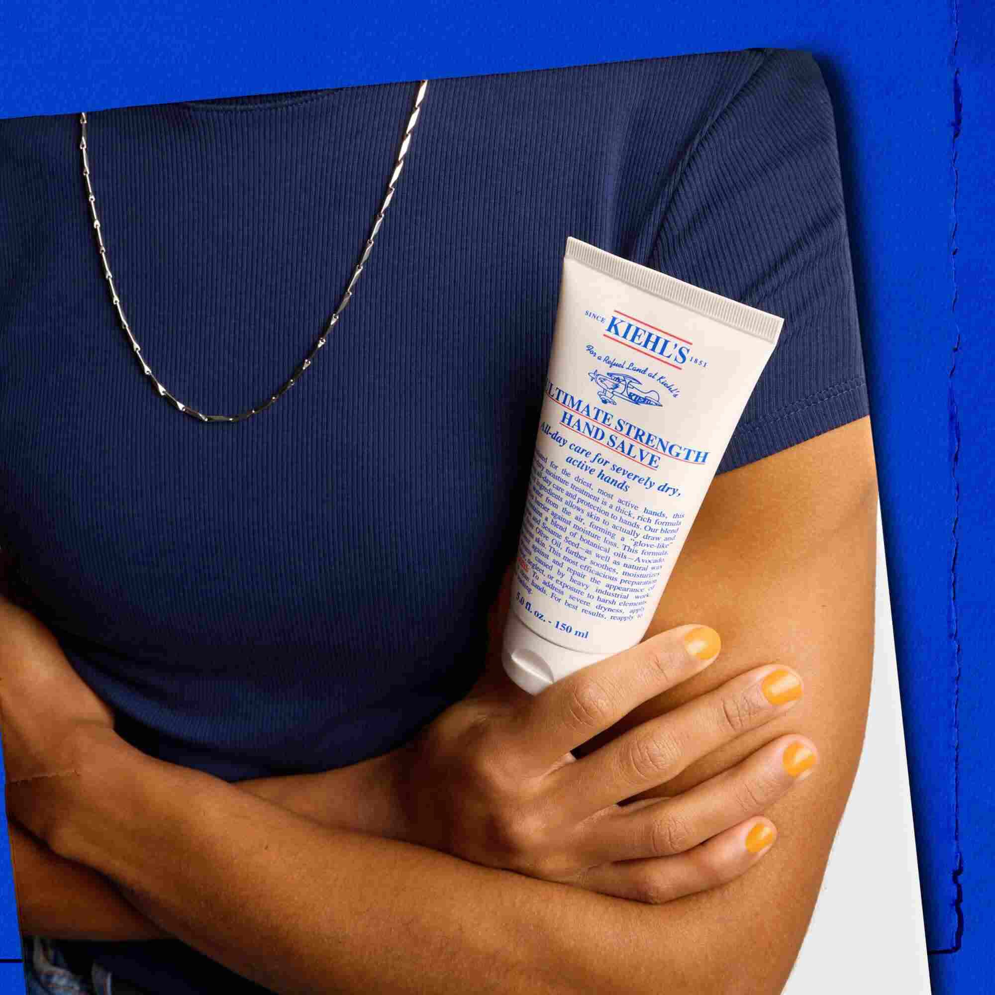 Модел, държящ тубичка Kiehl's Ultimate Strength Hand Salve