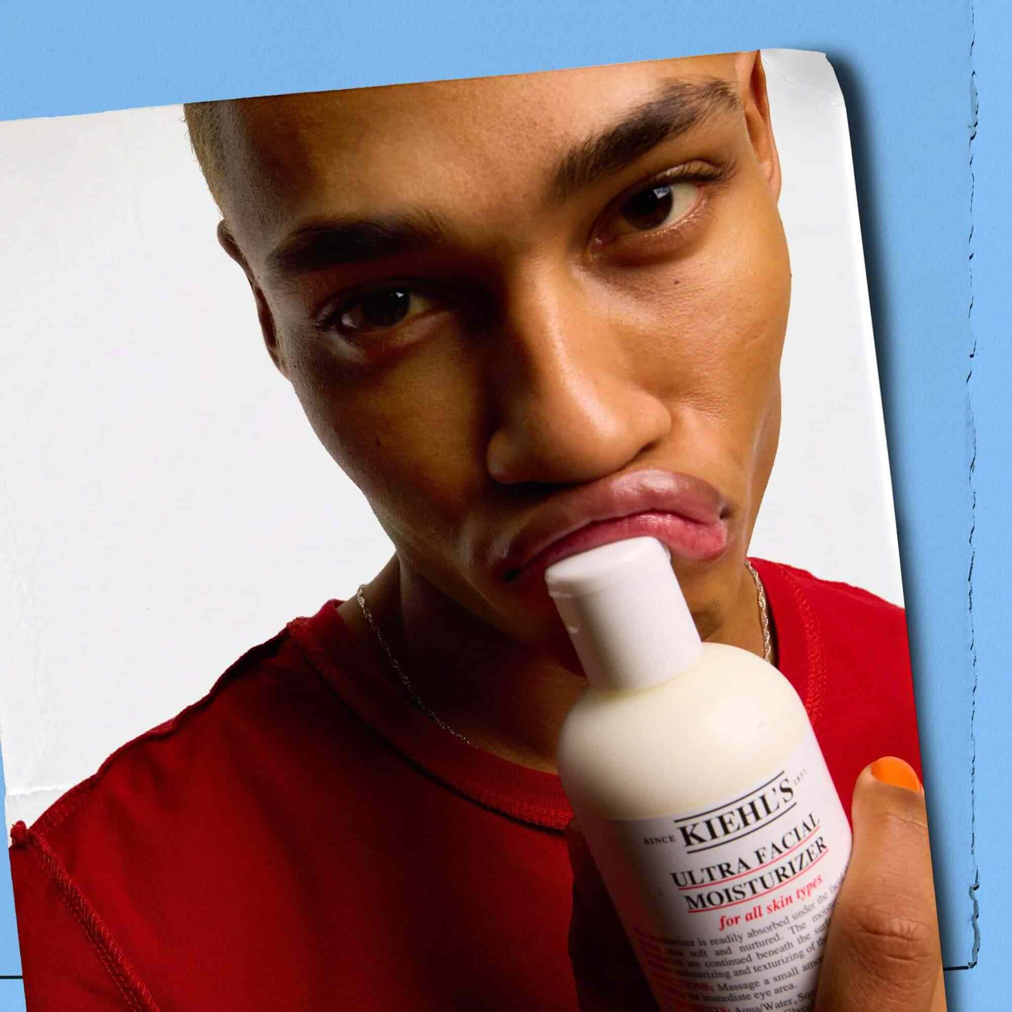 Модел, притискащ бутилка Kiehl's Ultra Facial Moisturizer към устните си