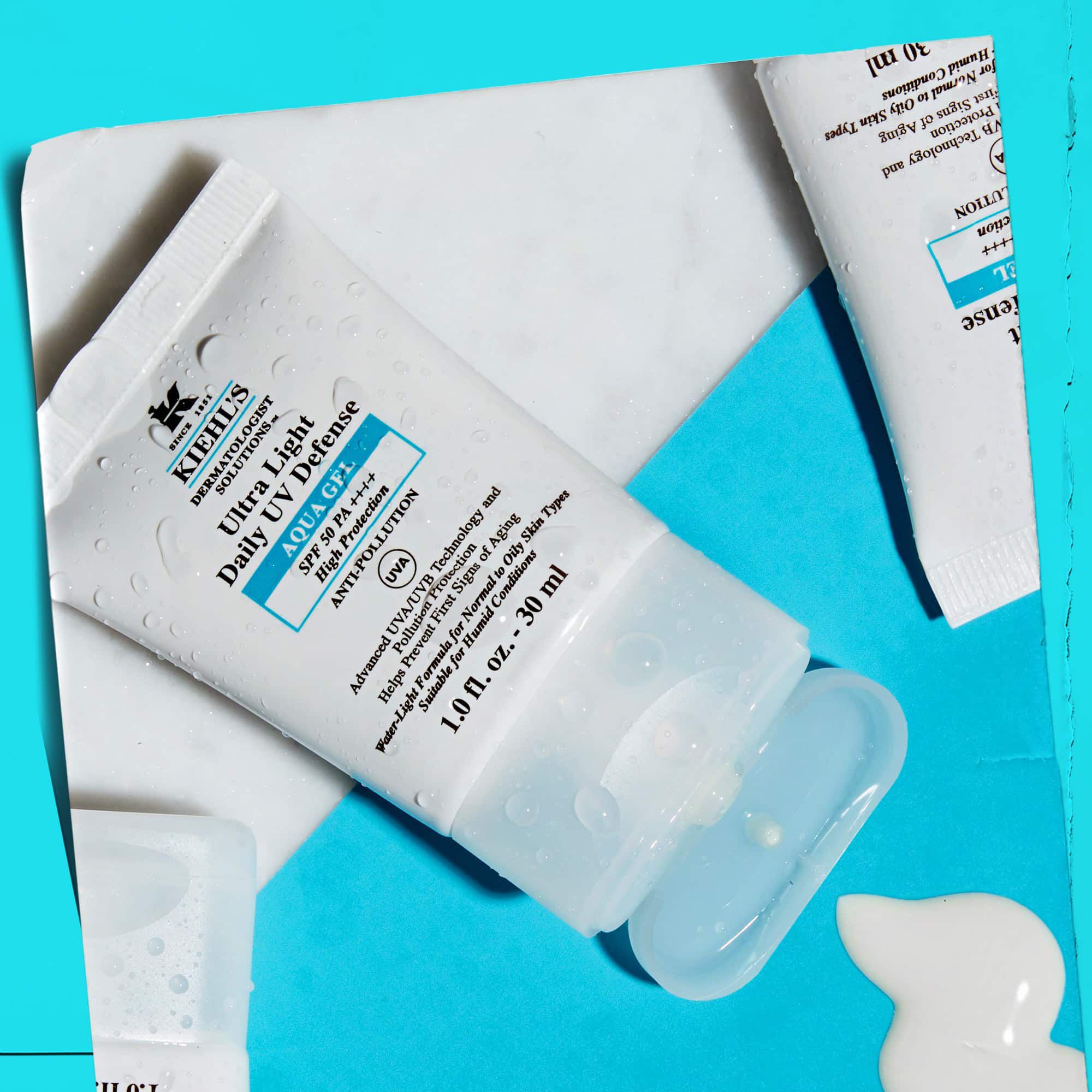 Разположение на множество туби Ultra Light Daily UV Defense Aqua Gel върху мраморна повърхност, показващо техния лайфстайл чар.