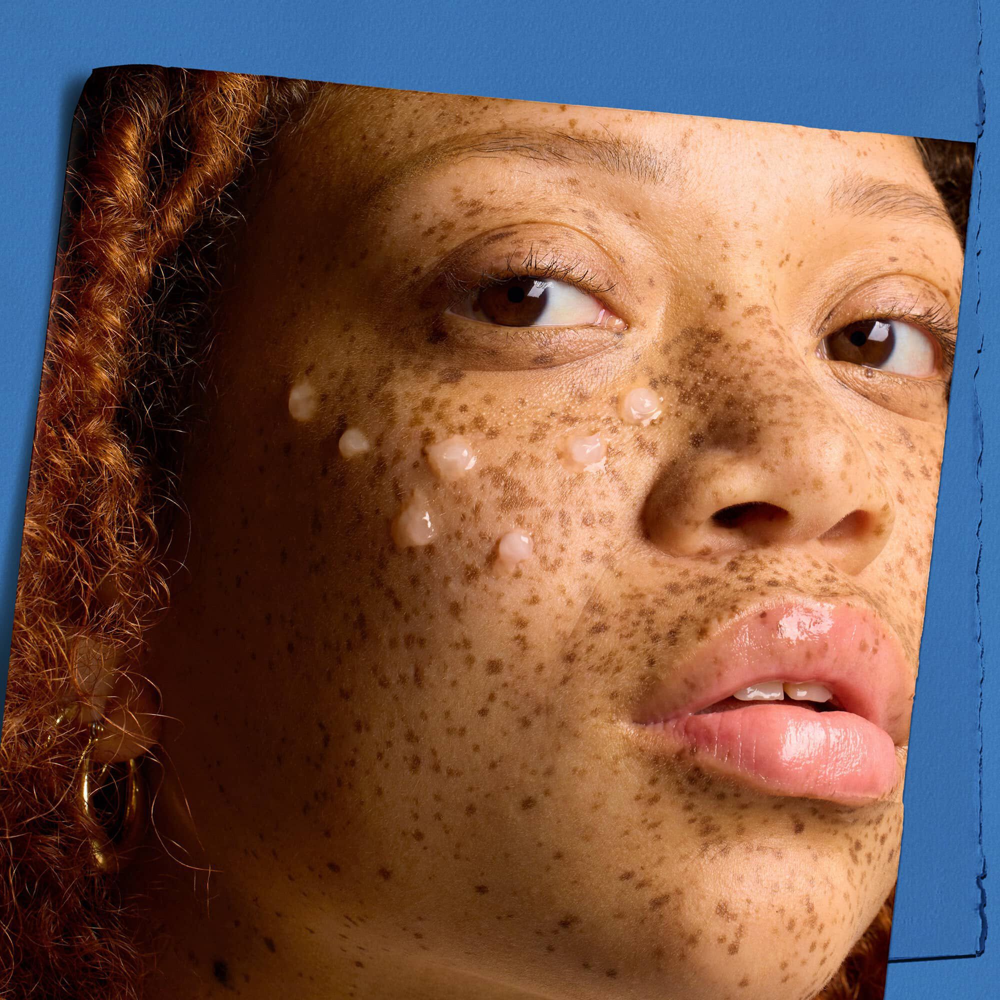 Модел с капки серум-концентрат Kiehl's Hydro Plumping върху лицето си