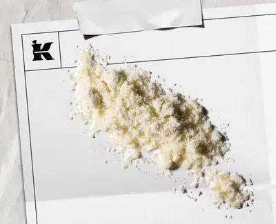 Бял прах, представляващ 1% колоидна овесена каша върху бял лист с черно лого на Kiehl's в ъгъла.