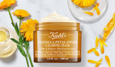 A jar of Kiehl's Calendula Petal-Infused Calming Mask, surrounded by calendula petals, emphasizing its soothing and skin-relieving properties.