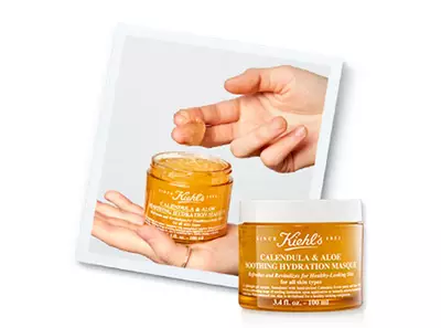 Ръка държи гел маска за хидратация на Kiehl's с календула и алое, пред фона на опаковката на продукта.