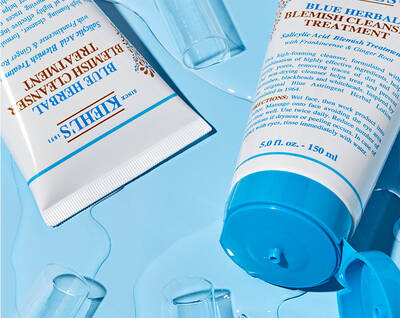 Тюбета с кремове за лечение на акне на Kiehl's на син фон с капки течност.