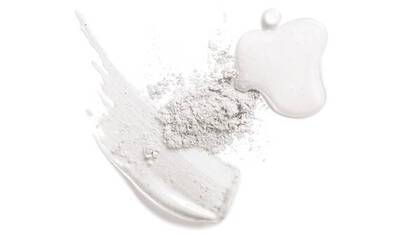 A flat lay of various textures featuring a white powder, a creamy white smear, and a glossy droplet resembling a cosmetic product.