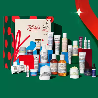 Празничен коледен календар и подаръчен комплект за грижа за кожата Kiehl's с различни кремове, серуми, почистващи продукти и целенасочена грижа на празнична експозиция.