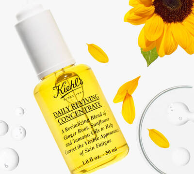 Бутилка с жълт серум за лице Kiehl's, за revitalizиране на кожата с масла от джинджифил и слънчоглед. Слънчогледови листенца около нея.