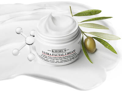 Крем за лице Kiehl's Ultra Facial в бял контейнер, обграден от маслиново клонче и кремообразна текстура.